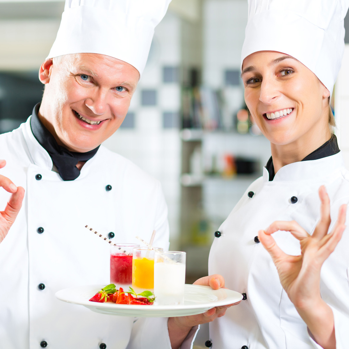 two chefs giving the OK sign holding fruit shooters