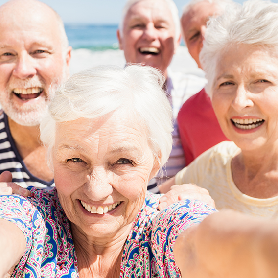 Group of seniors taking a selfie while enjoying a beautiful day at the beach