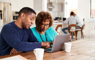 Senior woman looking at laptop with adult son researching senior living communities