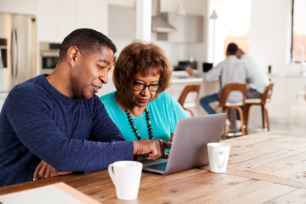 Senior woman looking at laptop with adult son researching senior living communities