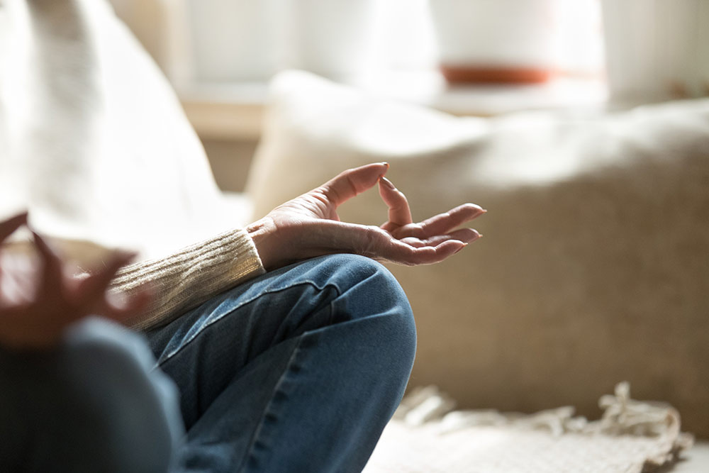 Close up of senior woman meditating on couch in living room