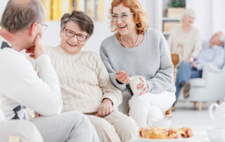 Happy seniors sitting on couch laughing and talking in senior living community