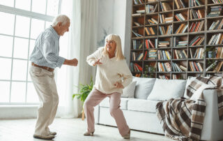Senior couple dancing in living room having fun and smiling
