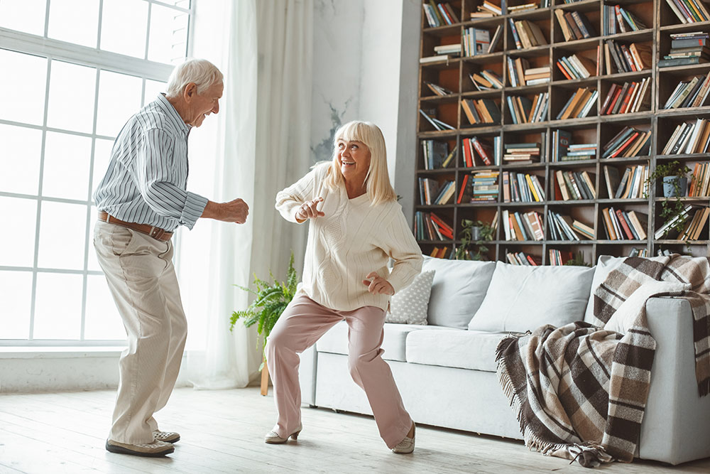 Senior couple dancing in living room having fun and smiling