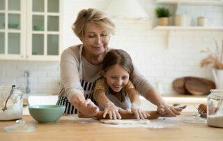 Senior woman baking with granddaughter in kitchen happy and smiling